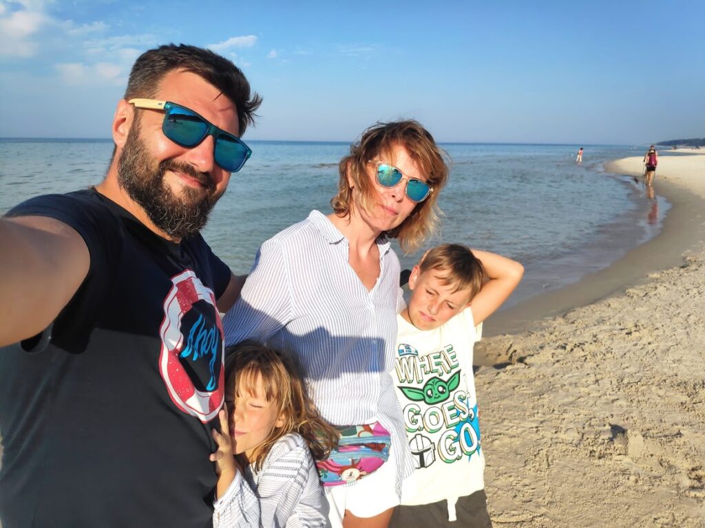 Gospodarze Villa NOVA Dębki – Piotr i [Twoje Imię] z dziećmi podczas spaceru na plaży w Dębkach
