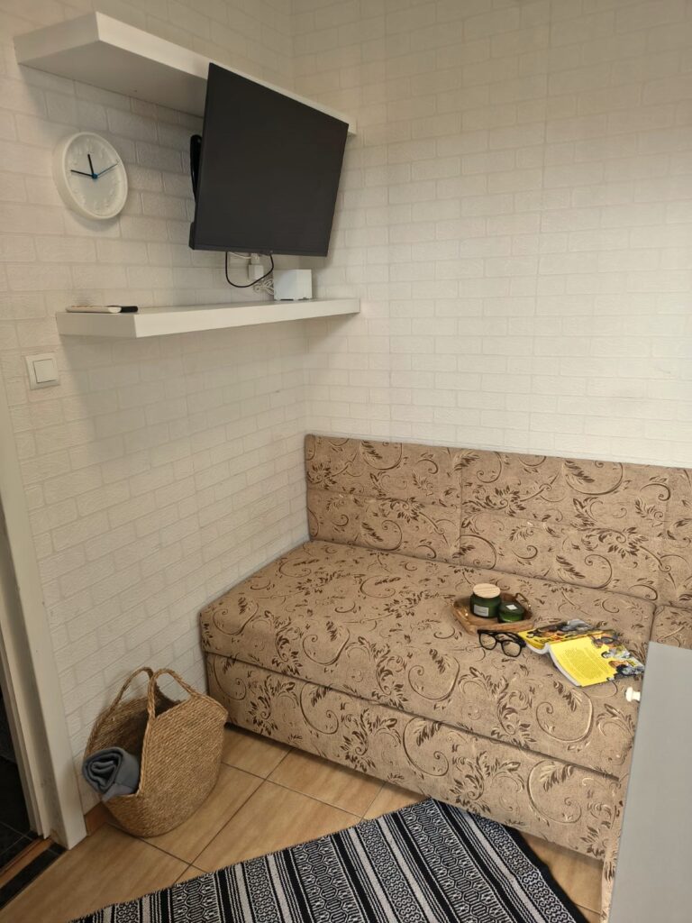 Wygodna sofa i telewizor na ścianie w przytulnym pokoju jednoosobowym w obiekcie Villa NOVA w Dębkach
