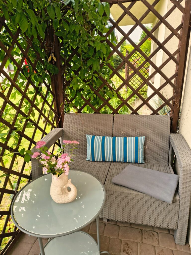 Wygodna sofa i stolik kawowy na prywatnym tarasie otoczonym zielenią w obiekcie Villa NOVA w Dębkach