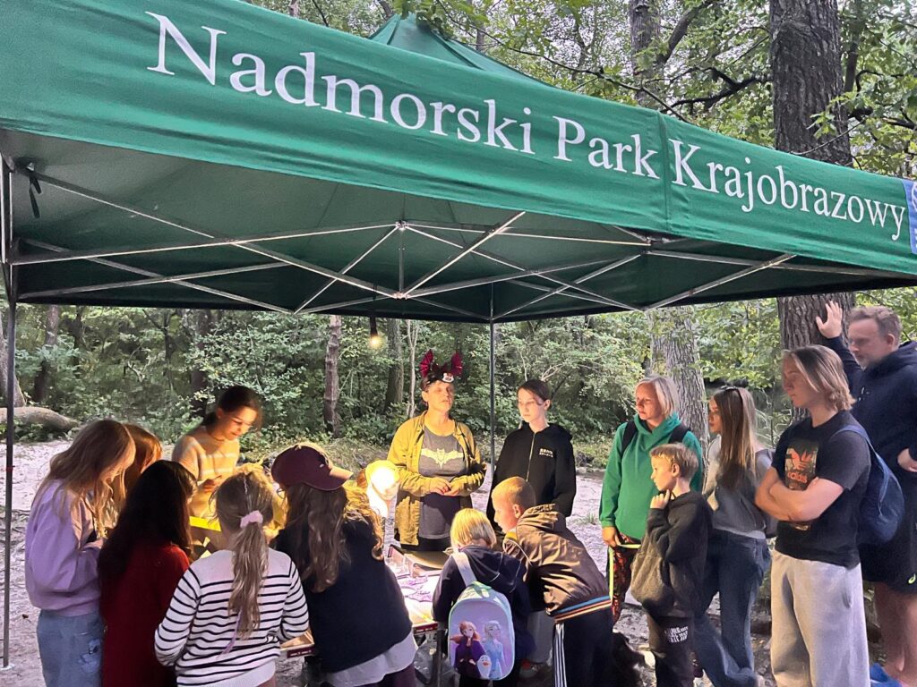 Uczestnicy warsztatów przyrodniczych wokół namiotu edukacyjnego Nadmorskiego Parku Krajobrazowego w Dębkach