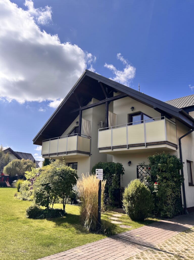 Fasada i balkony Villi NOVA w Dębkach otoczone zielenią i zadbanym trawnikiem