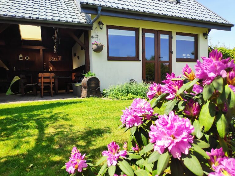 Kwitnące różowe rododendrony i zadaszona wiata grillowa w ogrodzie Villi NOVA w Dębkach